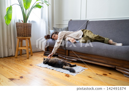 Positive peaceful woman lying on sofa interacting with beloved cat, living stress free and day break Positive peaceful woman lying on sofa interacting with beloved cat, living stress free and day break 142491874