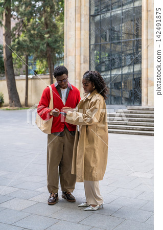 Couple of african american friends man and woman exchanging phone numbers while meeting in city. Couple of african american friends man and woman exchanging phone numbers while meeting in city. 142491875