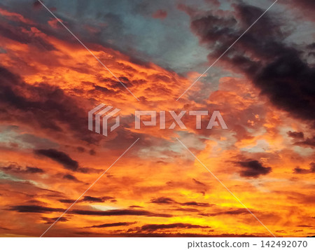 colorful orange sunset sky with dark cloud streaks colorful orange sunset sky with dark cloud streaks 142492070