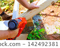 Construction worker is at work fastening wooden boards together using power nail gun tool. 142492381