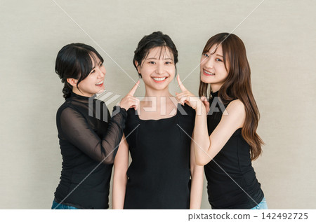 一位年輕的亞洲女性面帶微笑，與朋友聊著皮膚和美容的話題。 142492725