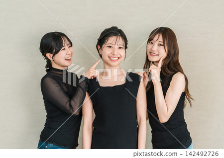 一位年輕的亞洲女性面帶微笑，與朋友聊著皮膚和美容的話題。 142492726
