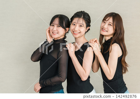 三位年輕的亞洲女性並肩合影，她們面帶微笑，看起來很友善。 142492876