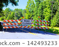 Road closed sign blocks access to rural road lined with trees 142493233
