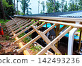 Builders construct framework to support roof on wooden beams 142493236