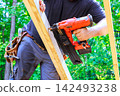 Workers is working on construction project with air nail gun wooden boards in wooded area 142493238