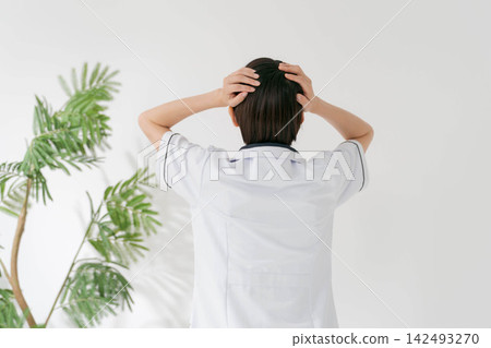 A female salon staff member holds her head in her hands. A female salon staff member holds her head in her hands. 142493270