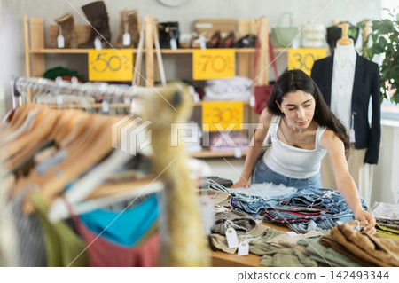 Woman in summer one chooses pants at a sale Woman in summer one chooses pants at a sale 142493344