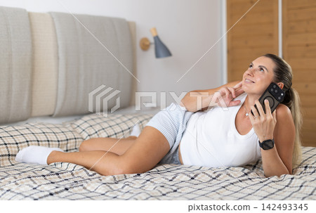Woman talking on smartphone in the background of bedroom interior 142493345
