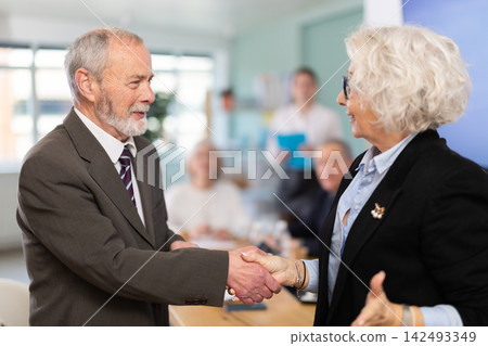Man and woman shake hands in gratitude after signing a contract at business meeting Man and woman shake hands in gratitude after signing a contract at business meeting 142493349