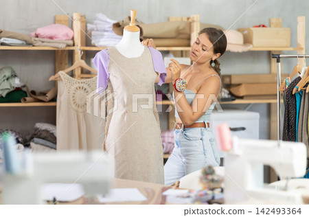 dressmaker stands near the mannequin in the workshop dressmaker stands near the mannequin in the workshop 142493364