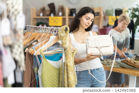 Armenian woman choosing a white handbag against the background of a buyer Armenian woman choosing a white handbag against the background of a buyer 142493368