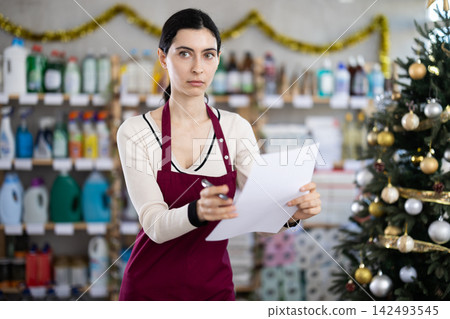 Female seller with paper document, plans to replenish restock stores inventory on Christmas Eve 142493545