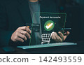 Close up of businessman holding credit card and smartphone with green payment successful icon hologram, online checkout and e-commerce concept. 142493559