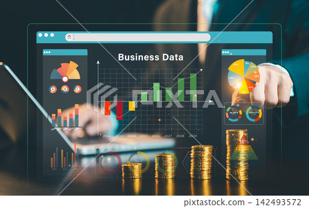 Businessman pointing at virtual business data web dashboard interface with gold coin stacks and growth chart overlay, financial analytics concept. Businessman pointing at virtual business data web dashboard interface with gold coin stacks and growth chart overlay, financial analytics concept. 142493572