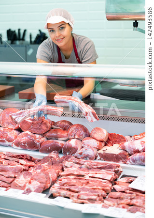 Young female butcher showing fresh raw veal short ribs Young female butcher showing fresh raw veal short ribs 142493586