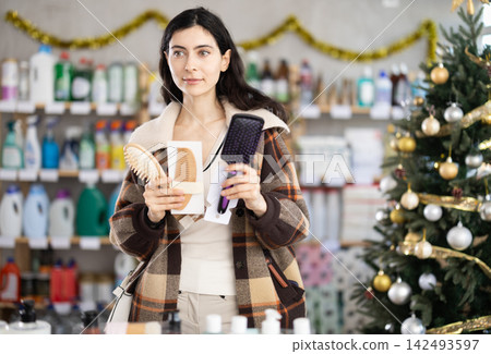 woman chooses a comb against the background of a Christmas tree woman chooses a comb against the background of a Christmas tree 142493597