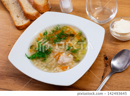 Tasty soup rassolnik served in bowl on table, decorated with parsley. Traditional russian dish Tasty soup rassolnik served in bowl on table, decorated with parsley. Traditional russian dish 142493645