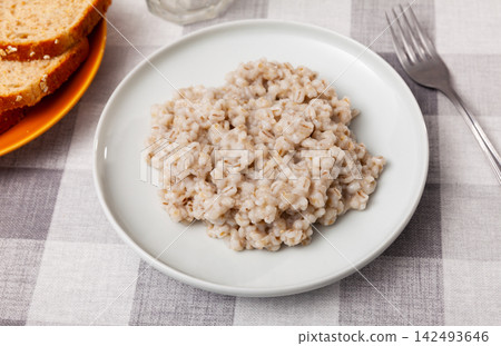 There is portion of freshly prepared milk pearl barley porridge in plate There is portion of freshly prepared milk pearl barley porridge in plate 142493646