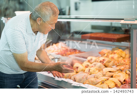 Elderly male customer points with finger and orders whole chicken fresh poultry 142493743