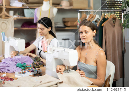 Female seamstresses working at sewing machines in tailoring studio 142493745