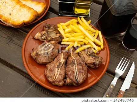 Dish with delicious appetizing baked pork cheeks with french fries for dinner close up Dish with delicious appetizing baked pork cheeks with french fries for dinner close up 142493746