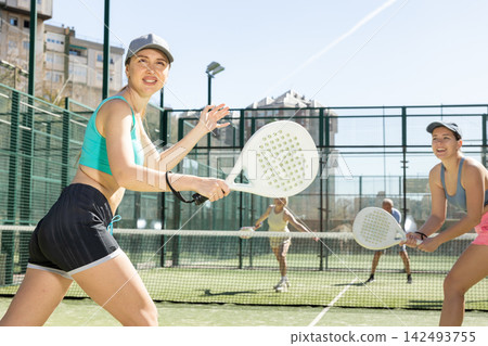 Two young sporty girls playing padel game in court on sunny day Two young sporty girls playing padel game in court on sunny day 142493755