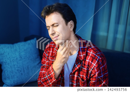 man experiencing a sore throat due to a seasonal cold or flu infection. This respiratory illness highlights home treatment, recovery, and feeling unwell during viral infections. man experiencing a sore throat due to a seasonal cold or flu infection. This respiratory illness highlights home treatment, recovery, and feeling unwell during viral infections. 142493756