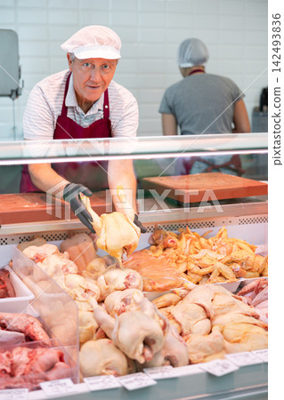 Adult man seller lays out chicken in butcher shop Adult man seller lays out chicken in butcher shop 142493836