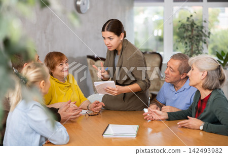 Young psychologist together with elderly adults have group therapy round table 142493982