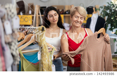Two women choosing clothes on sale in a store Two women choosing clothes on sale in a store 142493986