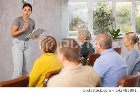 Young female tutor leading educational class for group of elderly Young female tutor leading educational class for group of elderly 142493991