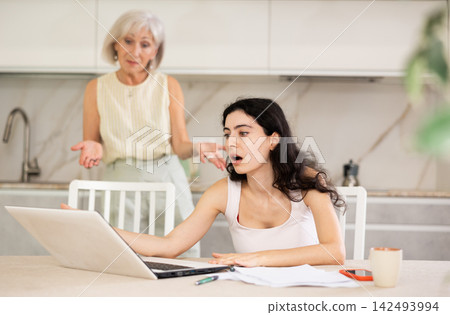 Elderly woman quarrels with young woman working at laptop Elderly woman quarrels with young woman working at laptop 142493994