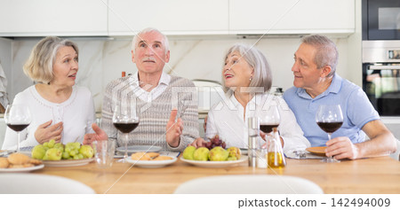 At the table, happy group of adults enjoy their holiday, drink wine and talk together At the table, happy group of adults enjoy their holiday, drink wine and talk together 142494009