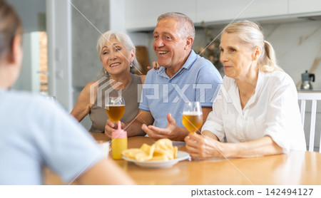 Elderly people drinking and chatting at table Elderly people drinking and chatting at table 142494127