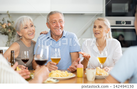 Happy seniors chatting at dinner table. Concept of happy life together in nursing home Happy seniors chatting at dinner table. Concept of happy life together in nursing home 142494130