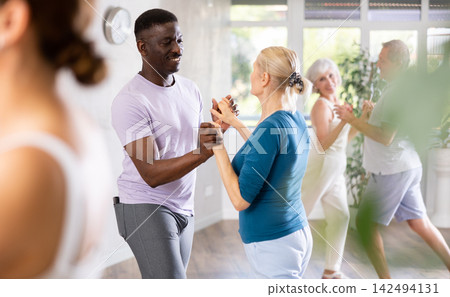 Senior woman dancing samba with african american man Senior woman dancing samba with african american man 142494131