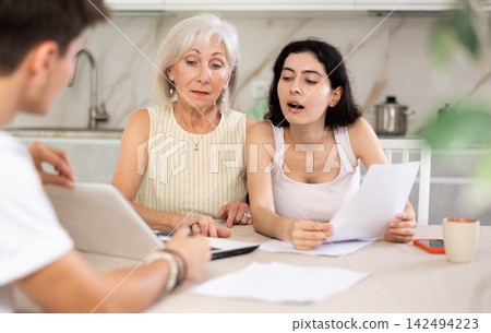 Male insurance agent offers the best insurance terms for an elderly woman and her adult daughter. Male insurance agent offers the best insurance terms for an elderly woman and her adult daughter. 142494223