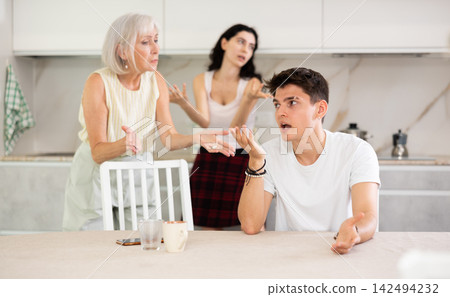 Elderly woman mother and young girl during family quarrel accuse adult son Elderly woman mother and young girl during family quarrel accuse adult son 142494232