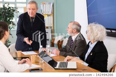 Senior business community listening to male speaker or presenter during round table conference. Senior business community listening to male speaker or presenter during round table conference. 142494266