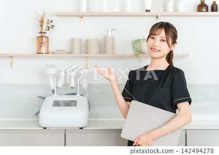 A young female esthetician staff member greets you with a smile at the beauty salon. A young female esthetician staff member greets you with a smile at the beauty salon. 142494278