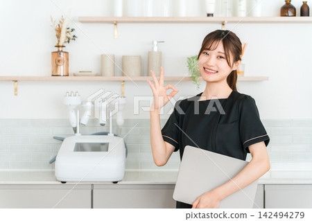 一位女美容師在美容院裡面微笑著比出「OK」的手勢。 142494279