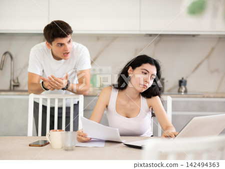 Young guy quarrels with young woman working at laptop Young guy quarrels with young woman working at laptop 142494363