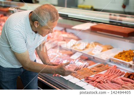 Adult man buyer chooses sausages in butcher shop 142494405