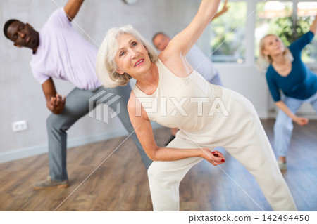 Active mature men and women practicing Jazz-funk dance in training hall Active mature men and women practicing Jazz-funk dance in training hall 142494450