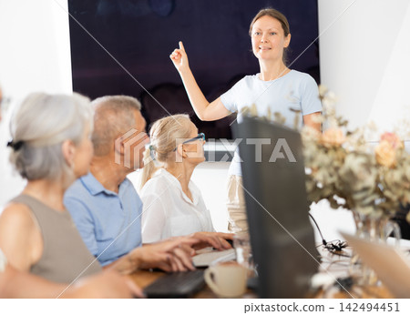 Woman teacher teaching elderly people how to use computer Woman teacher teaching elderly people how to use computer 142494451