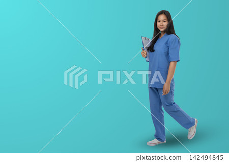 Woman in blue medical outfit holds clipboard in studio space Woman in blue medical outfit holds clipboard in studio space 142494845