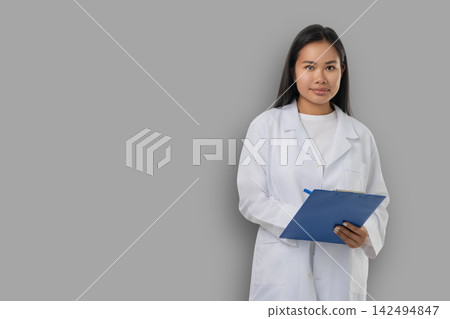 Medical worker stands with clipboard in a studio backdrop Medical worker stands with clipboard in a studio backdrop 142494847