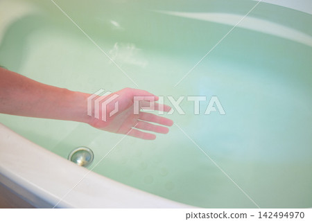 Check the water temperature in the bathtub. Check the water temperature in the bathtub. 142494970