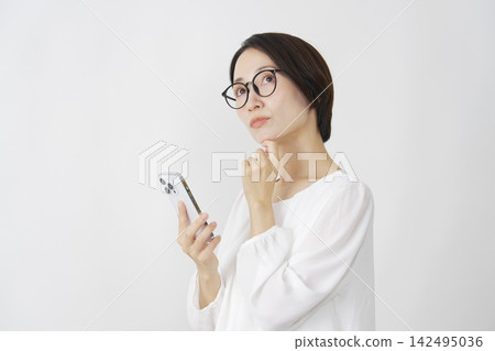 一位中年婦女在白色背景下使用智慧型手機思考。 142495036